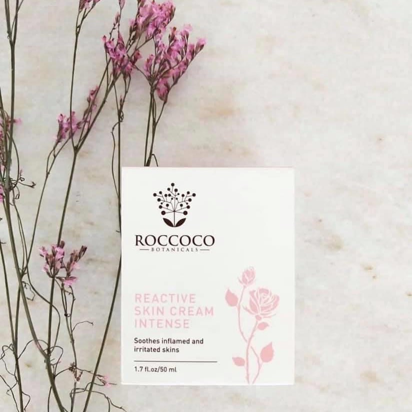 Box of Roccoco Reactive Skin Cream Intense the best hydration cream laying on marble with pink dried flowers on the left side 